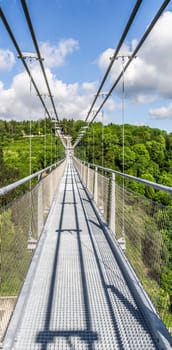 Suspension bridge over the Rappbode dam, with the forests of the Harz mountains in the background
