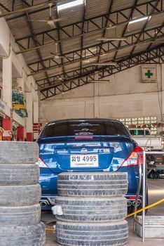 Bangkok, Thailand - December 30, 2017 : Unidentified car mechanic or serviceman disassembly and checking a car alloy chrome wheel for fix and repair suspension problem at car garage or repair shop