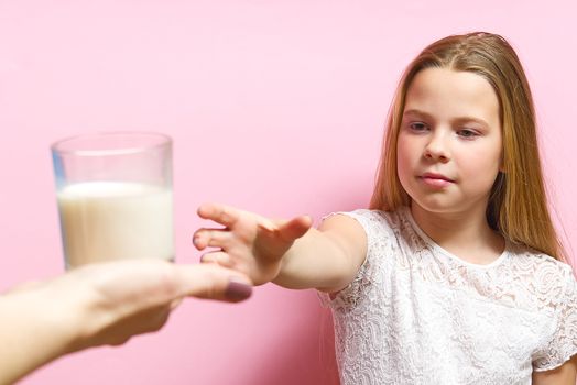 girl with pigtails and milk mustache drinks milk on pink background