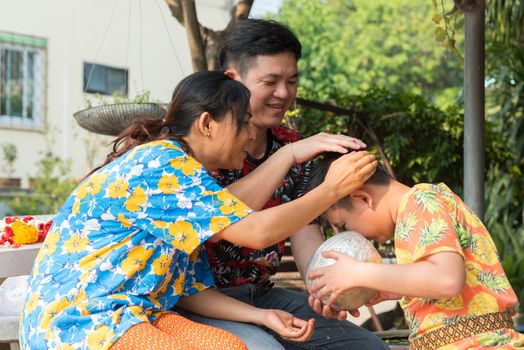 Ang Thong, Thailand - April 13, 2018 : Unidentified Asian young bathe with respect to parents by water have a jasmine and rose flower and aromatherapy in water in water bowl in Songkran Festival