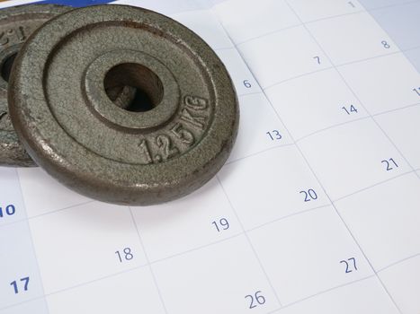 two weight plates on a white and blue calendar