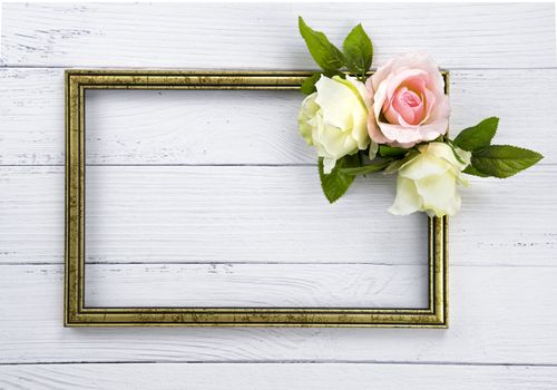 Gold colored vintage wooden frame decorated with beutiful pink and white roses. Template mock up. Copy space for text. White background.