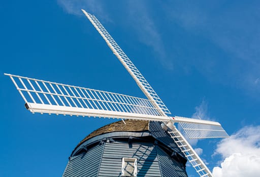 Top of vintage wind mill decorated with lights on blue sky background