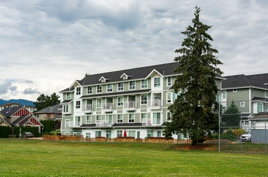 New residential low-rise building with huge green lawn in front on cloudy day in Canada