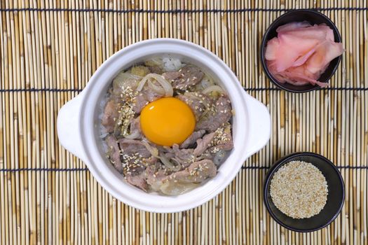 fried pork with onion and white sesame, topped with raw egg yolk, and eaten with prickled ginger