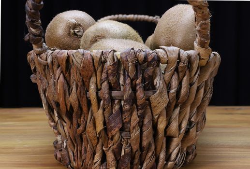 brown kiwi on a dry banana leaf basket on a wood top table