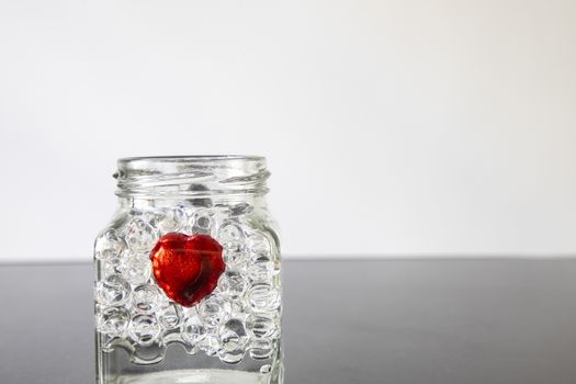 A red chocolate candy heart in a clear glass bottle. Black and white back blurred background