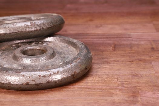 two old weight plates on brown natural wood background