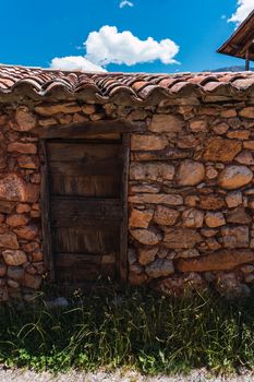 Rustic door of an abandoned farmhouse, made with stone walls in a village in the Pyrenees mountains.