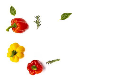 Colorful yellow, red, and orange bell peppers with rosemary sprigs and basil leaves on white background. Top view.