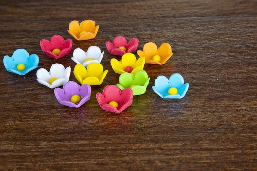 A group of colorful icing sugar flowers on brown wooden background
