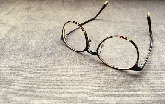 A pair of dark brown spectacles on a brown cotton sofa. Copy space.