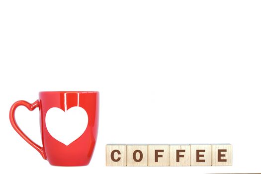 A red coffee mug with white heart pattern and wooden blocks with text spelling coffee. Isolated on white background.