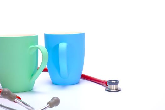 a red stethoscope and two colorful coffee mugs on white background