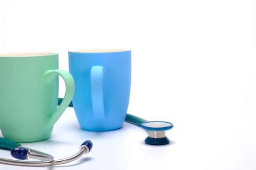 a green stethoscope and two colorful coffee mugs on white background