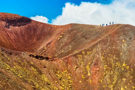 A group of people standing on the edge of the volcano crater, Mount Etna, Sicily, Italy