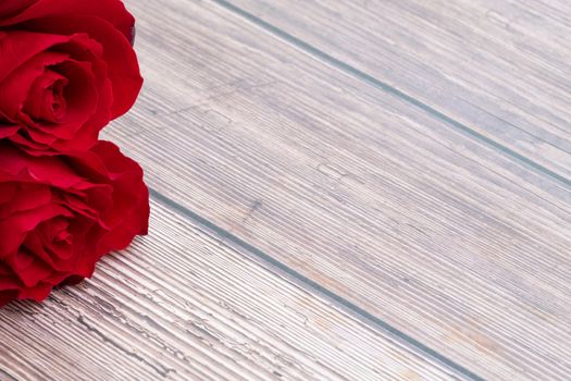 beautiful red roses on brown wooden background. Copy space.