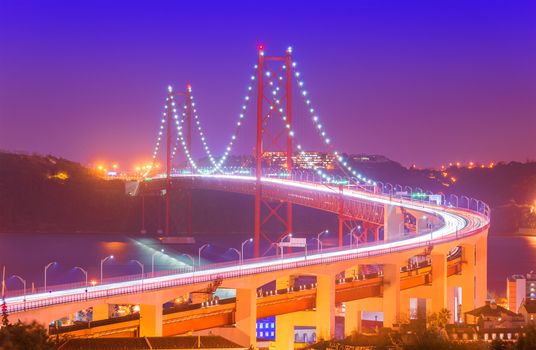 View of The 25th April Bridge (Ponte 25 de Abril) with car light trails in haze. Popular landmark of Lisbon, Portugal