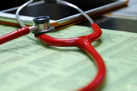 a red stethoscope and a tablet on a typical doctor's desk