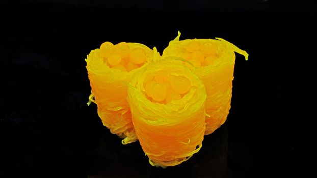 Thai Dessert with Portuguese origin, 'Sweet Egg Floss', is made of egg yolk and syrup, seen here shaped like bird nest and tiny eggs, isolated on black background