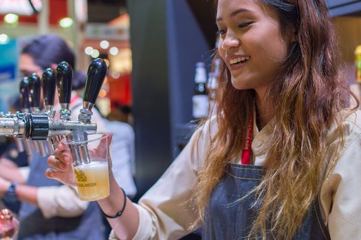 Bangkok, Thailand - May 28, 2016 : Unidentified barman or bartender pouring a draught lager beer from beer tap on counter for serving in a restaurant or pub.