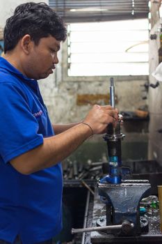 Bangkok, Thailand - May 28, 2016 : Unidentified serviceman checking shock absorber in car suspension at garage