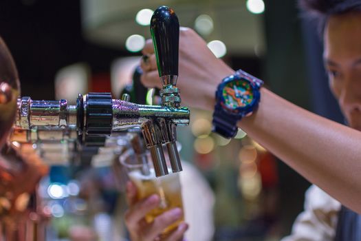 Bangkok, Thailand - May 28, 2016 : Unidentified barman or bartender pouring a draught lager beer from beer tap on counter for serving in a restaurant or pub.