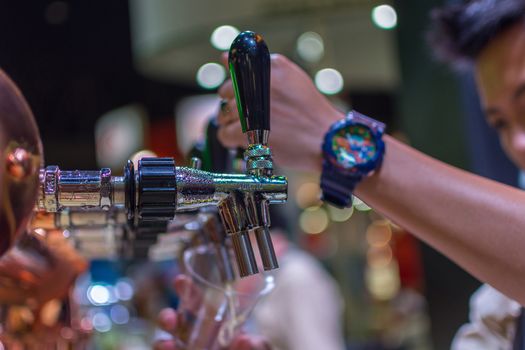 Bangkok, Thailand - May 28, 2016 : Unidentified barman or bartender pouring a draught lager beer from beer tap on counter for serving in a restaurant or pub.