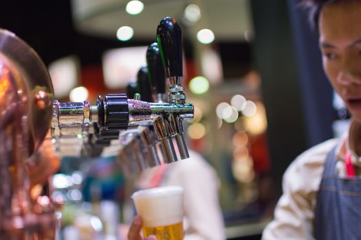 Bangkok, Thailand - May 28, 2016 : Unidentified barman or bartender pouring a draught lager beer from beer tap on counter for serving in a restaurant or pub.