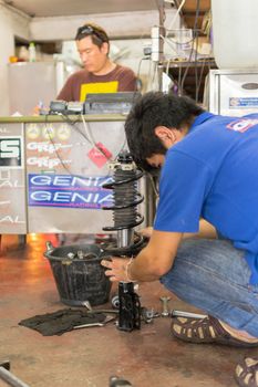 Bangkok, Thailand - January 22, 2016 : Unidentified serviceman checking suspension in a car at garage