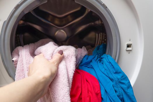 girl takes out the laundry from the washing machine. woman puts clothes in a washing machine.
