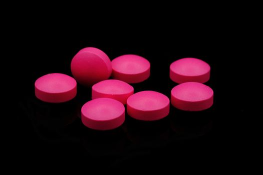 pink medicine tablets on black background