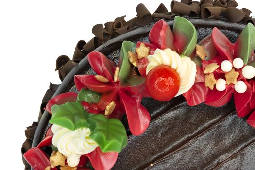 A chocolate cake decorated with red, white and green flowers and leaves, appropriate for Christmas and New Year celebration. Top view, closed up, isolated on white background with copy space.