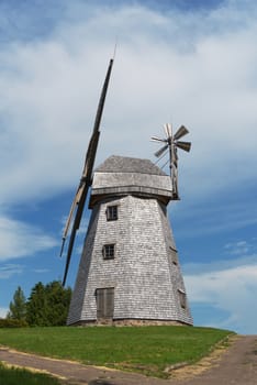 Old windmill in grassland in a country landscape under a cloudy blue sky in a scenic landscape