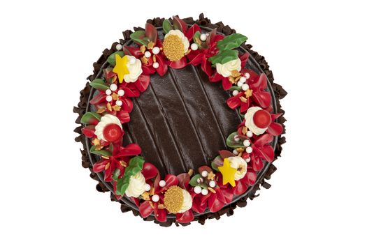 A chocolate cake decorated with red, white and green flowers and leaves, appropriate for Christmas and New Year celebration. Top view, closed up, isolated on white background with copy space.