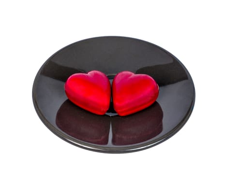 two heart shape chocolate candies on a black ceramic plate, isolated on white background, valentine's day concept