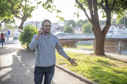 Man talking on smartphone in park, outdoor shoot, back light