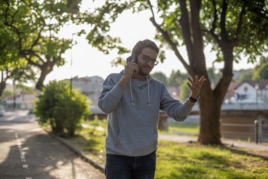 Man talking on smartphone in park, outdoor shoot, back light