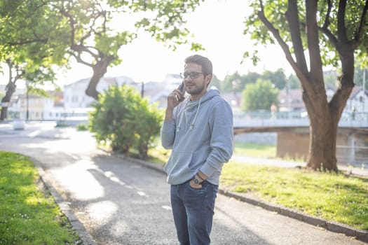 Man talking on smartphone in park, outdoor shoot, back light