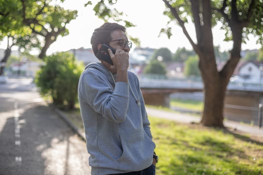 Man talking on smartphone in park, outdoor shoot, back light