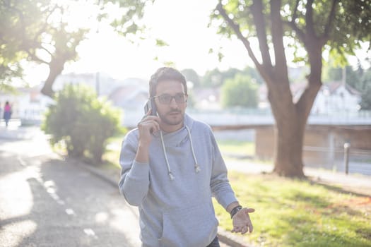 Man talking on smartphone in park, outdoor shoot, back light