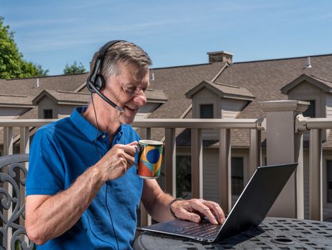 Senior caucasian man working from home during coronavirus epidemic using headset and laptop to communicate
