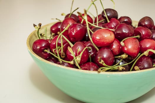 close up red cherries in bowl on white background