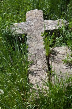 Antique fallen stone cross in the grass