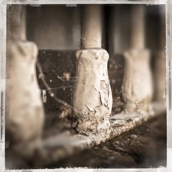 Old window bars with peeling paint, dirt and cobwebs. Vintage style frame. Defocused blurry background.