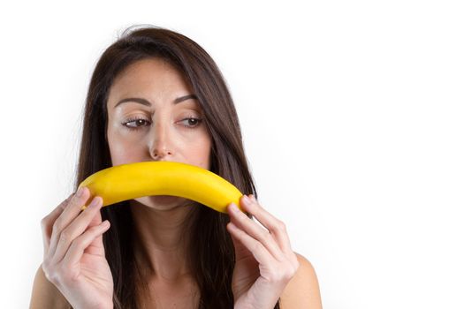 Creative portrait of woman holding yellow banana in her hand. Young sad woman with fruit and looking into camera