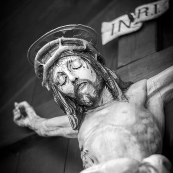 The bleeding body of Jesus Christ, crucified on a wooden cross. Shallow depth of field.