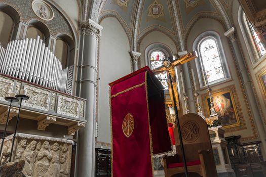 Catholic church interior. On the altar a crucifix and a red liturgical parament.