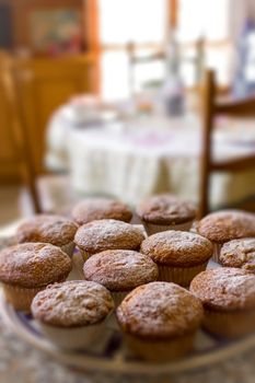 Batch of homemade freshly baked cupcakes or muffins on a plate in the kitchen in a close up view with selective focus. Defocused blurry background.