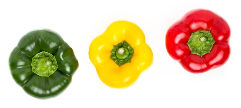 Three peppers of different colors lie in a row on a white background. Their colors are green yellow and red, and recall an Italian traffic light.
